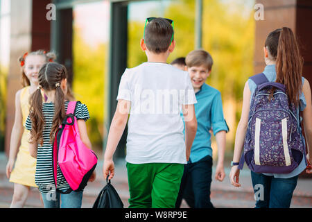 Compagni di scuola andare a scuola. Gli studenti salutarci. Foto Stock