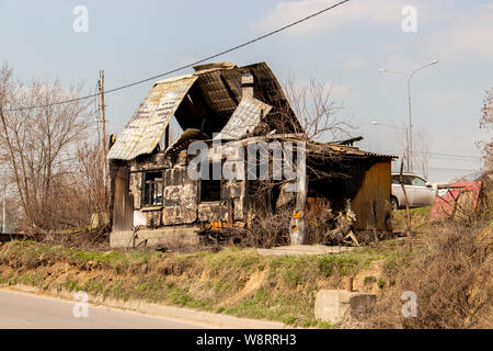 Lo scheletro di un olocausto casa in legno, una casa di abitazione dopo un incendio, senza trattamento. Villaggio in rovina casa, windows carbonizzati, tetto incavate, incendio doloso, un Foto Stock