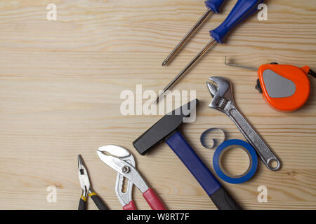 Strumenti di riparazione su un tavolo di legno. Cacciavite a martello misura nastro nastro adesivo chiave. Un set di attrezzi per la riparazione di apparecchiature Foto Stock