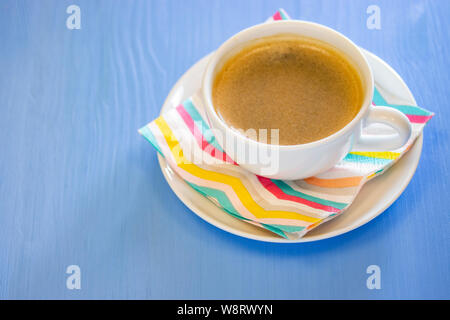 Una tazza di caffè con schiuma bianca porcellana ceramica, rigato colore igienico. Blu sullo sfondo di legno. Foto Stock