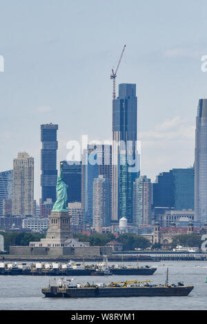 La Statua della Libertà e il porto di New York e di spedizione di imbarcazioni - New York skyline di costruzione in background Foto Stock