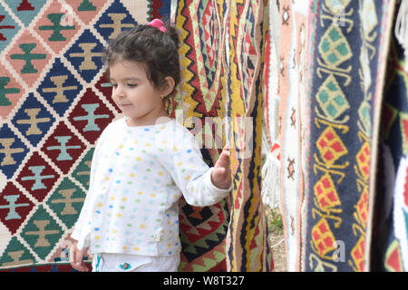 Bambina ritratto nella parte anteriore del coloratissimo kilim con motivi geometrici Foto Stock