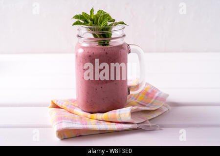 Frullato di frutti di bosco fatta con fragola, banana, succo di zenzero in un barattolo di vetro, su sfondo bianco Foto Stock