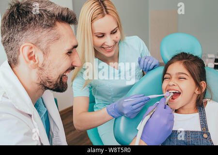 Dentista e il suo assistente sono trattare i denti di una bambina. Odontoiatria Pediatrica Foto Stock