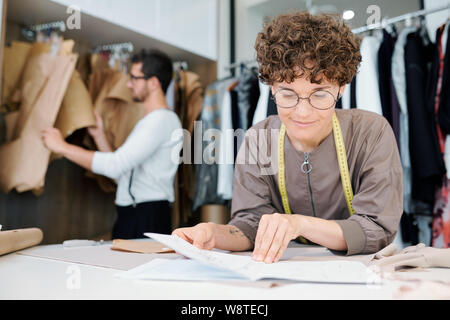 Giovani femmine sarta o designer di moda guardando il disegno del nuovo modello Foto Stock