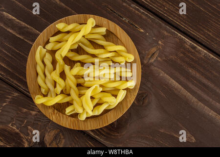 Sacco di tutta la pasta grezza gemelli sulla piastra di bambù flatlay su legno marrone Foto Stock