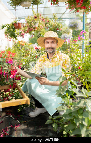 L'agricoltore contemporaneo nella ricerca di indumenti da lavoro per i nomi dei nuovi tipi di fiori Foto Stock