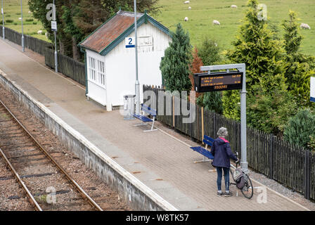 Passeggeri con bicicletta sotto il segno di destinazione in attesa ScotRail treno alla stazione di Strathcarron, NW Highlands della Scozia. Foto Stock