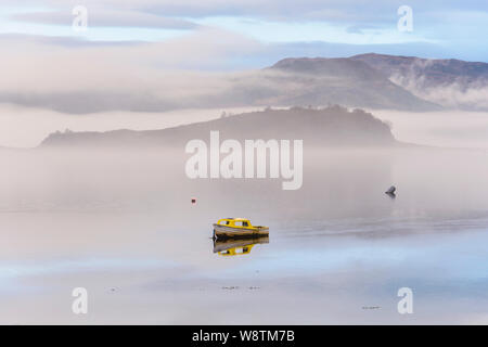 Piccola barca nella nebbia e nebbia sul Loch Carron, Wester Ross, Highlands della Scozia Foto Stock