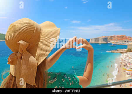 Giovane bella donna in Dubrovnik rendendo le mani a forma di cuore sulla primavera estate calda giornata di sole. Ragazza con hat felice all'aperto nel suo viaggio nel sud della C