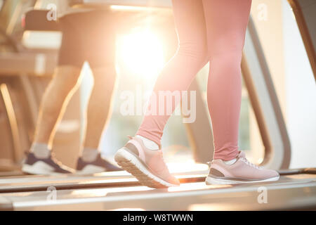 Sfondo di sport di persone in esecuzione sul tapis roulant in palestra illuminate dalla luce del sole, spazio di copia Foto Stock