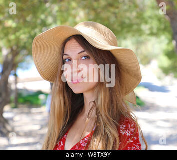 Ritratto di donna bella in estate cappello di paglia sorridente e guardando a voi mentre passeggiate sotto gli ulivi Foto Stock