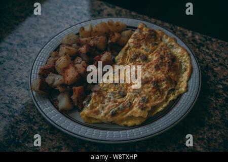 Primo piano di un'omelette e carne di maiale su un piastra Foto Stock