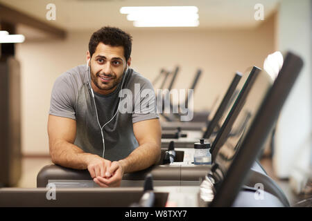 Ritratto di uomo muscolare prendendo break da allenamento in palestra e ascolto di musica, spazio di copia