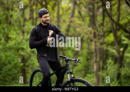 Maschio di mountain biker acqua potabile nella foresta Foto Stock