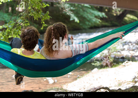 Un giovane adolescente si rilassa in una amaca mentre guardando a un fiume nel Parco Meeks su Giugno 9, 2018 in Blairsville, GA. Foto Stock