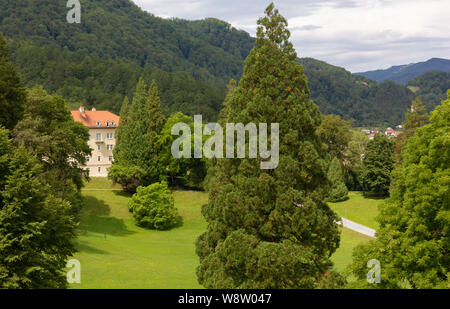 Grande parco tra verdi colline con alberi secolari e un edificio storico in background Foto Stock