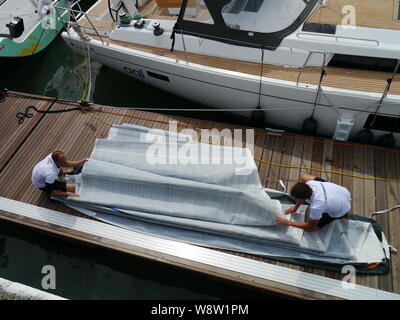 Cowes, Isle of Wight/UK- 11 Agosto 2019: due membri del team di yacht da regata preparare le loro vendite nella famosa annuale di regate a Cowes. Foto Stock