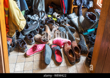 Un assortimento di scarpe, stivali e giacche in un armadio all'interno di un vecchio 1826 cottage in stile fieldstone house Foto Stock