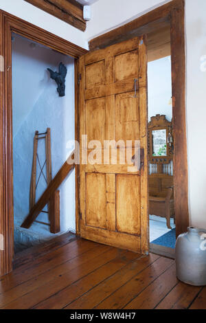 Porta aperta della scala nel soggiorno che porta giù al seminterrato all'interno di un vecchio cottage stile fieldstone casa 1820. Foto Stock