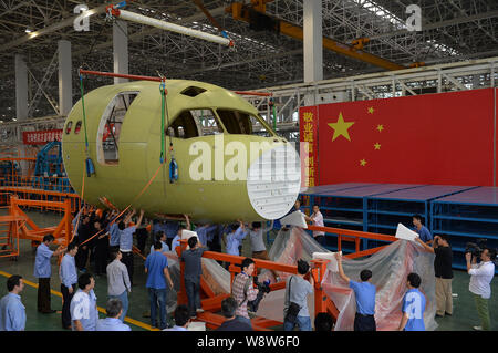Ingegneri cinesi e tecnici direttamente una gru per spostare il naso della Cina il primo la produzione nazionale di fatto jet del passeggero aereo C919 presso lo stabilimento di Chengdu Foto Stock