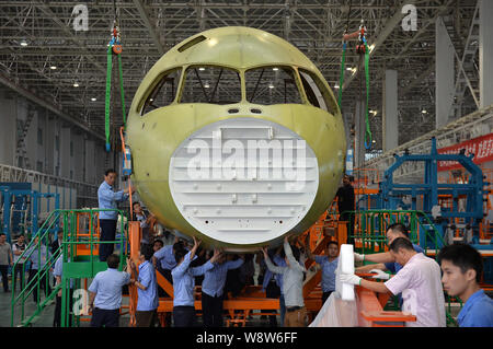Ingegneri cinesi e tecnici direttamente una gru per spostare il naso della Cina il primo la produzione nazionale di fatto jet del passeggero aereo C919 presso lo stabilimento di Chengdu Foto Stock