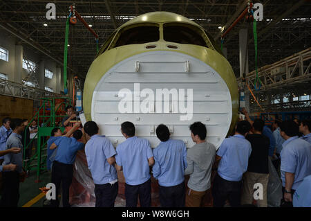 Ingegneri cinesi e tecnici direttamente una gru per spostare il naso della Cina il primo la produzione nazionale di fatto jet del passeggero aereo C919 presso lo stabilimento di Chengdu Foto Stock