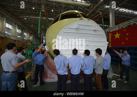 Ingegneri cinesi e tecnici direttamente una gru per spostare il naso della Cina il primo la produzione nazionale di fatto jet del passeggero aereo C919 presso lo stabilimento di Chengdu Foto Stock