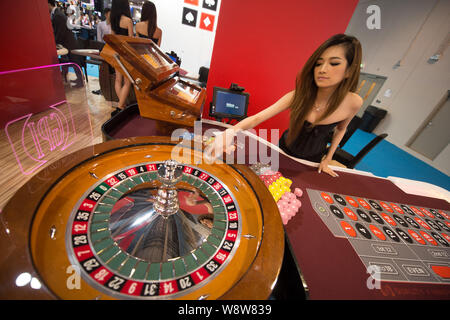 --FILE--una giovane donna dimostra una ruota della roulette durante il settimo Global Gaming Expo Asia (G2E Asia 2013) a Macau, Cina, 22 maggio 2013. Il gioco d'azzardo ri Foto Stock