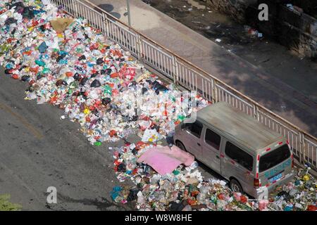 Un minivan è circondato da cumuli di rifiuti a sinistra su una strada in città Shiyan, città di Shenzhen, Cina del sud della provincia di Guangdong, 20 novembre 2014. Cina Foto Stock