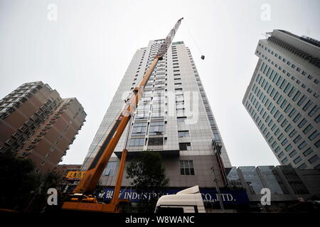 Un 260-ton heavy-duty gru viene utilizzata per demolire un illegalmente-costruzione sul tetto di un alto edificio di uffici a Pechino in Cina, 25 giu Foto Stock