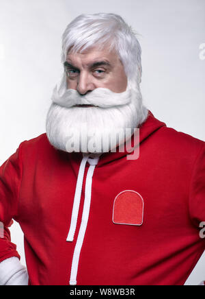 Ritratto di una Santa Claus in sportsware. Bianco-dai capelli uomo anziano con barba e baffi cercando nella fotocamera. Foto Stock