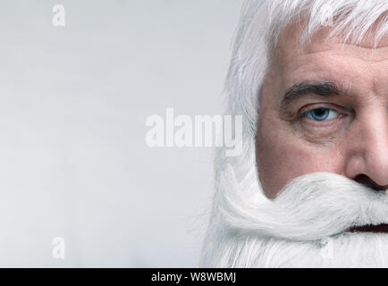 Close-up di un volto di Santa Claus. Bianco-dai capelli uomo anziano con barba e baffi cercando nella fotocamera. Foto Stock