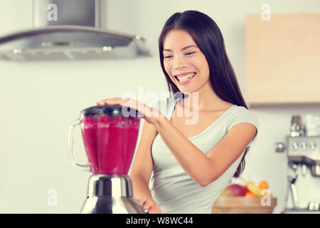 I frullati donna fare frullati di frutta con Blender. Mangiare sano stile di vita concetto Ritratto di giovane e bella donna preparando drink miscelazione di fragole, lamponi e frutti di bosco home in cucina. Foto Stock