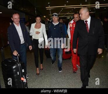Finnish F1 driver Kimi Raikkonen di Ferrari, centro e la sua fidanzata Minttu Virtanen, seconda a sinistra, camminare verso l'uscita al Shanghai Pudong Int Foto Stock