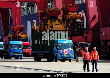 --FILE--lavoratori cinesi a piedi passato contenitore carrelli essendo caricati su una banchina del porto di Qingdao nella città di Qingdao, est Chinas provincia di Shandong, 13 Ma Foto Stock