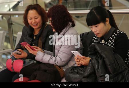 --FILE--le donne cinesi utilizzano il loro smartphone per navigare in Internet a un centro commerciale per lo shopping nella città di Xuchang, porcellane centrale provincia di Henan, 22 febbraio 2014. Foto Stock