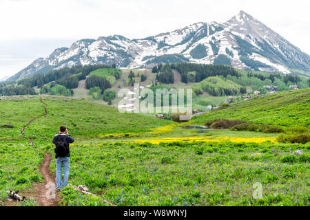 Uomo in piedi prendendo immagini sul sentiero Snodgrass con fotocamera e sfondo bokeh vista del monte Crested Butte, picco di Colorado Foto Stock