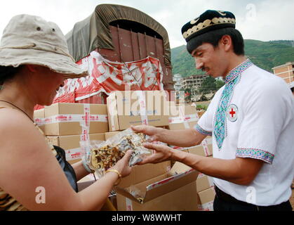 Cinese imprenditore Uighur Adil Memettur, destra, distribuisce il dado dolci (Qiegao) ha donato per gli abitanti dei villaggi locali colpite dal 6,5-terremoto di magnitudine Foto Stock