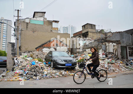 --FILE--un ciclista passa i detriti di vecchie case demolite per la riqualificazione in una baraccopoli in Cina a Shanghai, 14 novembre 2013. La Cina sarà Foto Stock