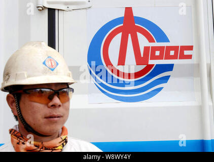 --FILE--un lavoratore cinese sta in piedi di fronte ad un contenitore con il logo di CNOOC (China National Offshore Oil Corporation) al petrolio Offshore Engineering Q Foto Stock