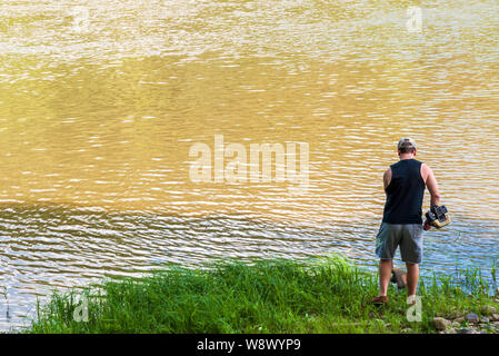 Un uomo con un erbaccia whacker per tagliare erba lungo il fiume Allegheny nella Contea di Warren in estate, Althom, Pennsylvania, STATI UNITI D'AMERICA Foto Stock