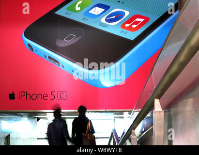 --FILE--pedoni a piedi sotto un annuncio pubblicitario per iPhone 5c di smartphone Apple in Cina a Shanghai, 7 marzo 2014. Chinas influente membro broadc Foto Stock