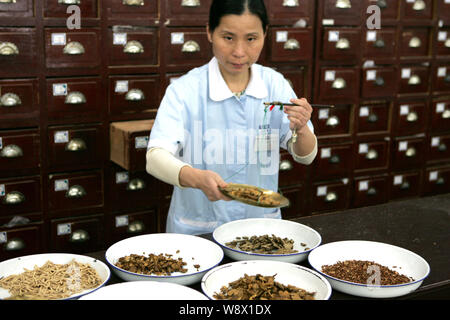 --FILE--un cinese pharmaceutist eroga la medicina tradizionale cinese in un TCM farmacia in Cina a Shanghai, 14 novembre 2011. Un secolare Chine Foto Stock