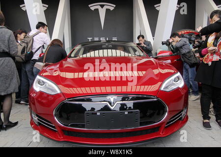 --FILE--persone guardano o scattare delle foto di un modello di Tesla S auto elettrica erogata al suo proprietario al centro vendita di Tesla in Jinqiao, Shanghai, Cina Foto Stock