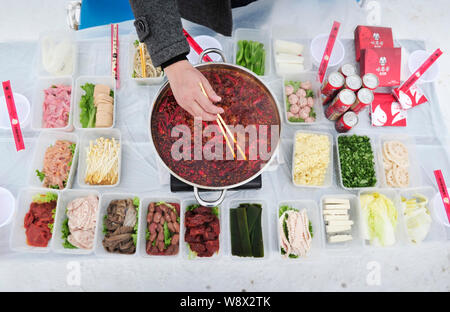 Un Cinese hotpot prepara ventola hot pot presso una stazione sciistica Xiling sulla montagna di neve in Dayi county, Chengdu, Cina sud-occidentale della provincia di Sichuan, 16 dic Foto Stock