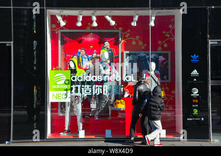 --FILE--pedoni guardare nella vetrina di un abbigliamento sportivo Adidas Store di Sanlitun Village, Pechino, Cina, 4 febbraio 2013. Il primo Adidas nuove Foto Stock