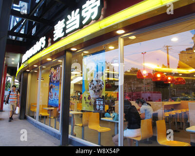 --FILE--A passeggiate a piedi passato un McDonalds un fast food ristorante a Shanghai in Cina, 8 luglio 2014. McDonald's Corp. ha sostituito la sua più grande fornitore Foto Stock