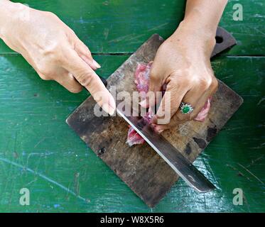 Primo piano del processo di taglio della carne con il coltello su un tagliere. Foto Stock