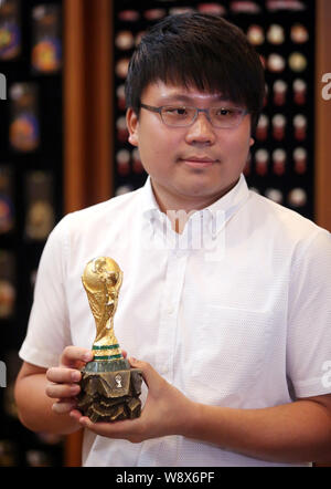 Li Zheyu, general manager di Dongguan carro oggettistica Co. Ltd, pone con una miniatura del FIFA World Cup Trofeo nel suo ufficio presso la fabbrica del carro in D Foto Stock